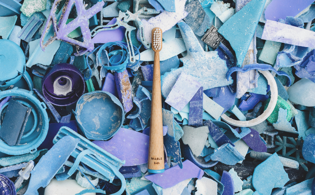 MABLE Bamboo toothbrush surrounded by blue colorful ocean plastic waste