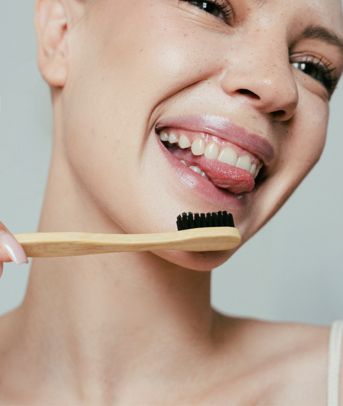 Person holding a MABLE wooden toothbrush with black bristles against a neutral background