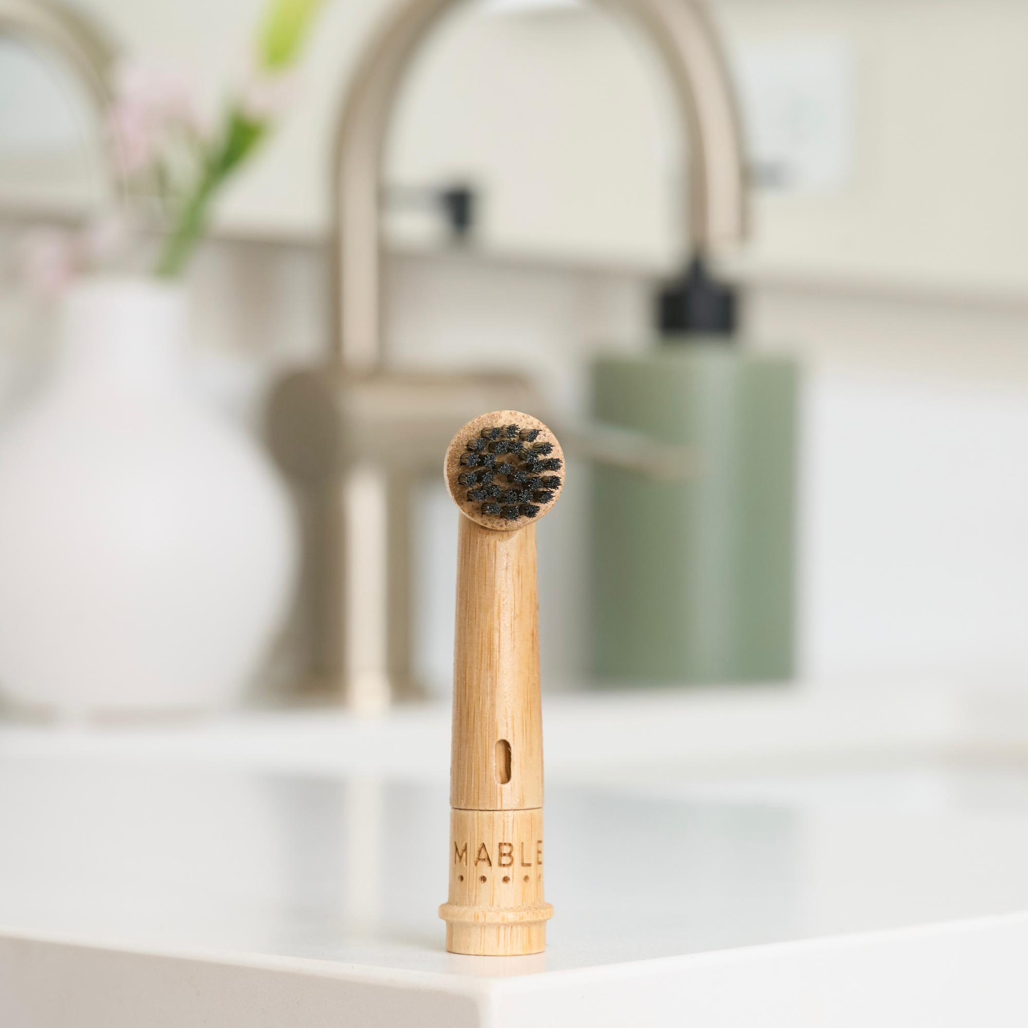MABLE Bamboo toothbrush head for Oral-B on a bathroom counter with blurred background