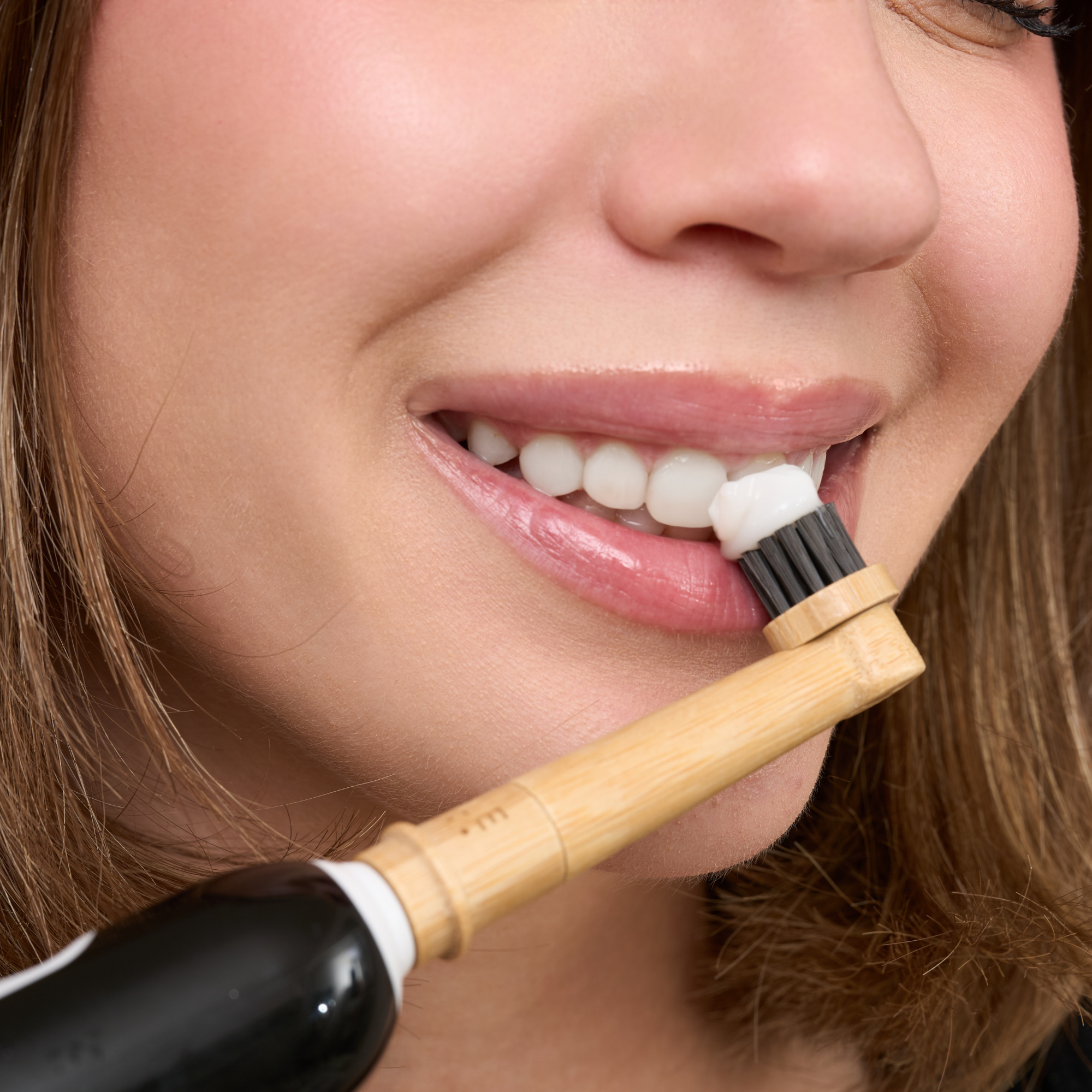 MABLE bamboo head for Oral-B rotating toothbrush in a women's smiling mouth