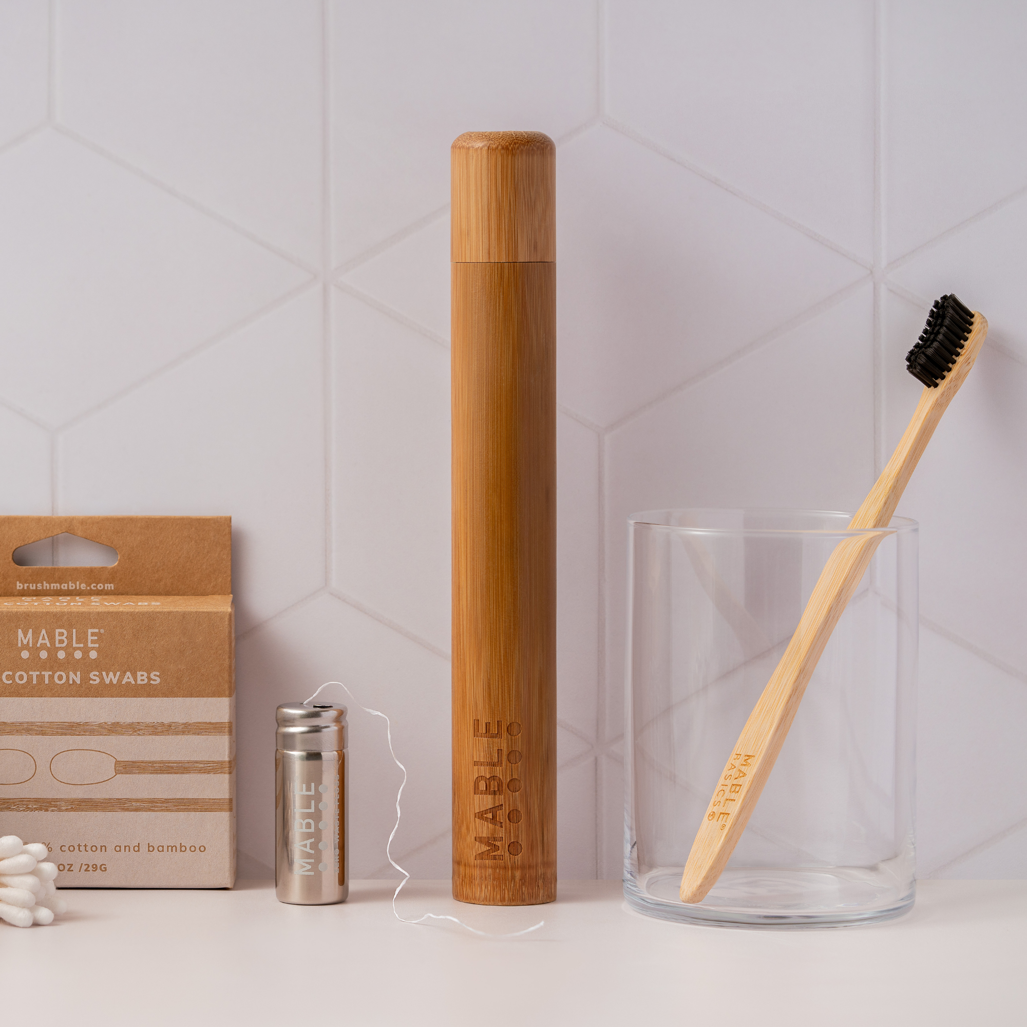 The most sustainable toothbrush by MABLE with a 100% compostable bamboo handle and plant-based bristles made from castor-bean oil on a bathroom backdrop with other eco bathroom products
