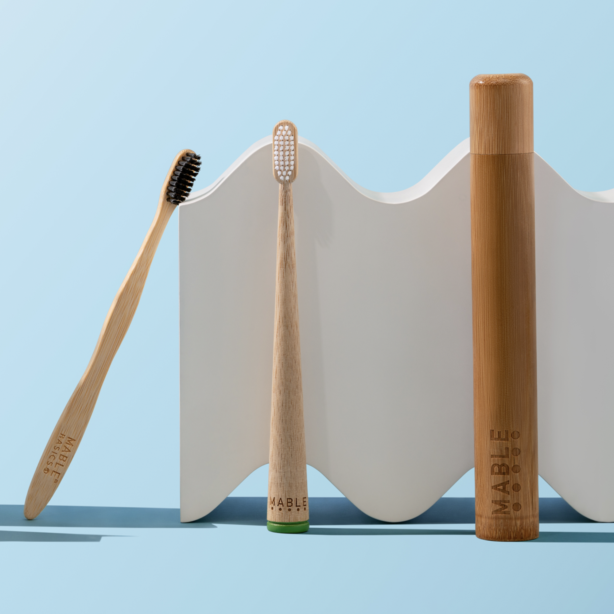 MABLE Bamboo toothbrushes and travel case on a light blue background