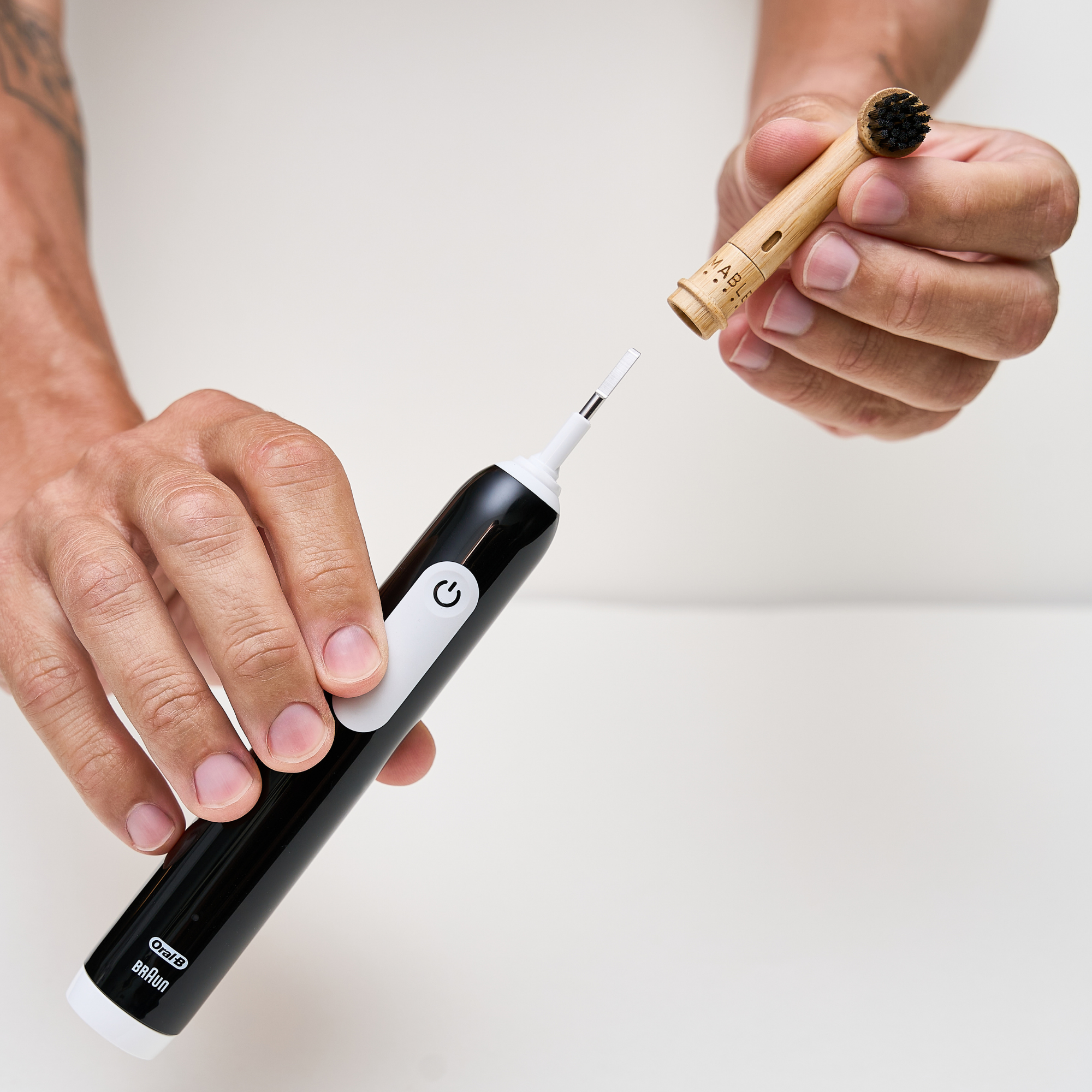 MABLE bamboo toothbrush head for Oral-B, mans hands showing the sustainable toothbrush head connecting to the oral-b toothbrush on a light grey background