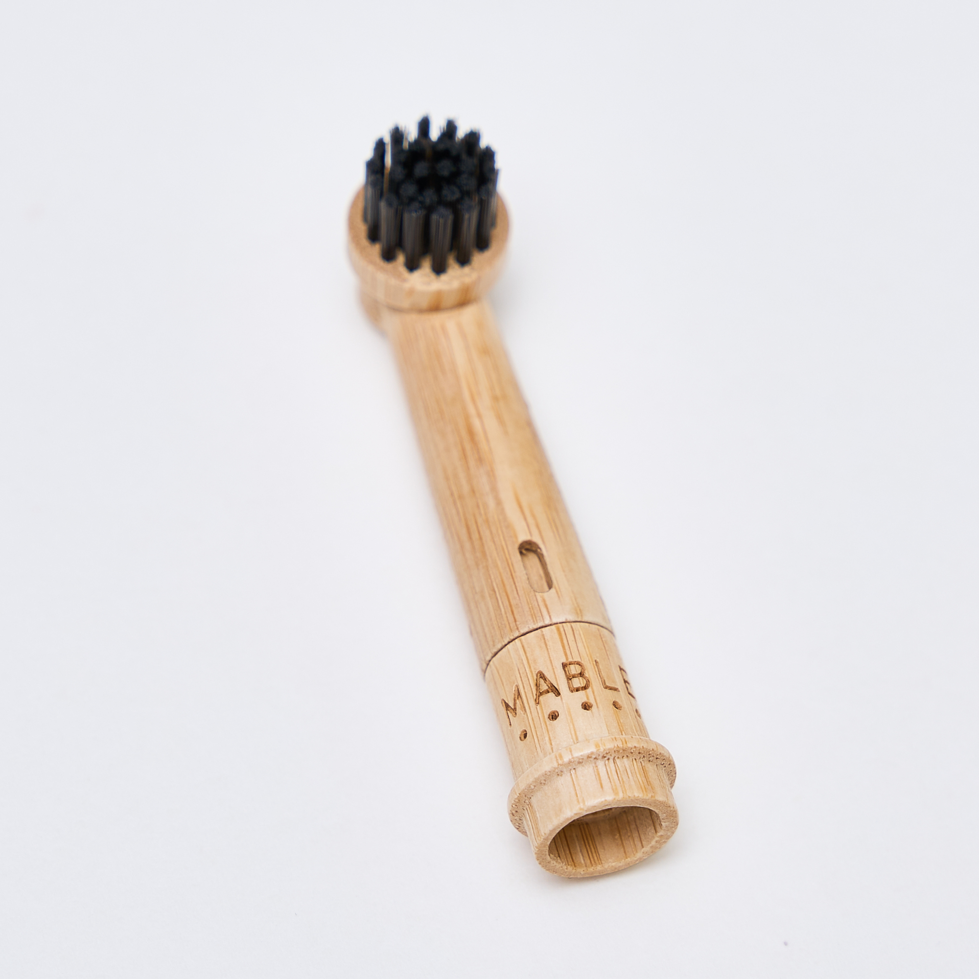 MABLE bamboo toothbrush head for Oral-B showing a compostable bamboo base and soft black bristles made from castor-bean oil