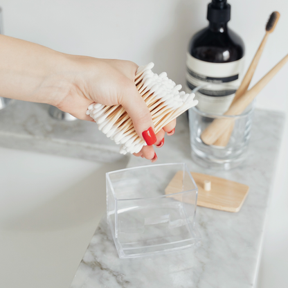 The best compostable ear swabs being held by a female hand and placed in a clear box holder
