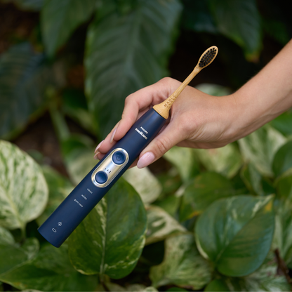 The best Eco-friendly Sonicare-compatible electric toothbrush heads by MABLE, shown as a bamboo replacement head with plant-based bristles on a navy blue electric toothbrush against a leafy background