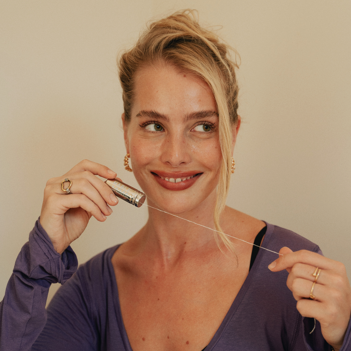 MABLE Compostable silk floss in a refillable stainless steel container being pulled out by a woman smiling 