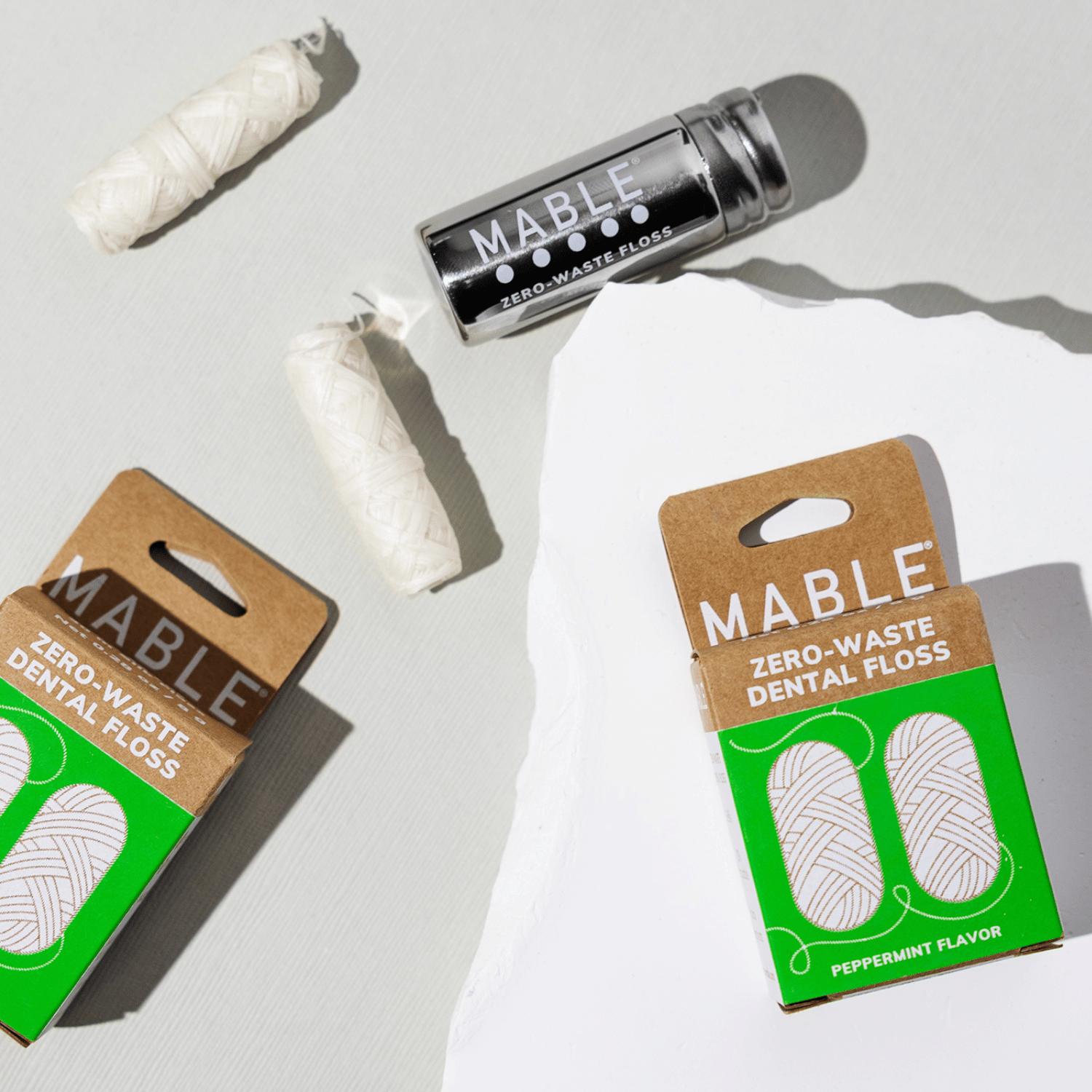 MABLE dental floss in a stainless steel refillable dental floss container pictured with eco-freindly dental floss refills made from natural ingredients