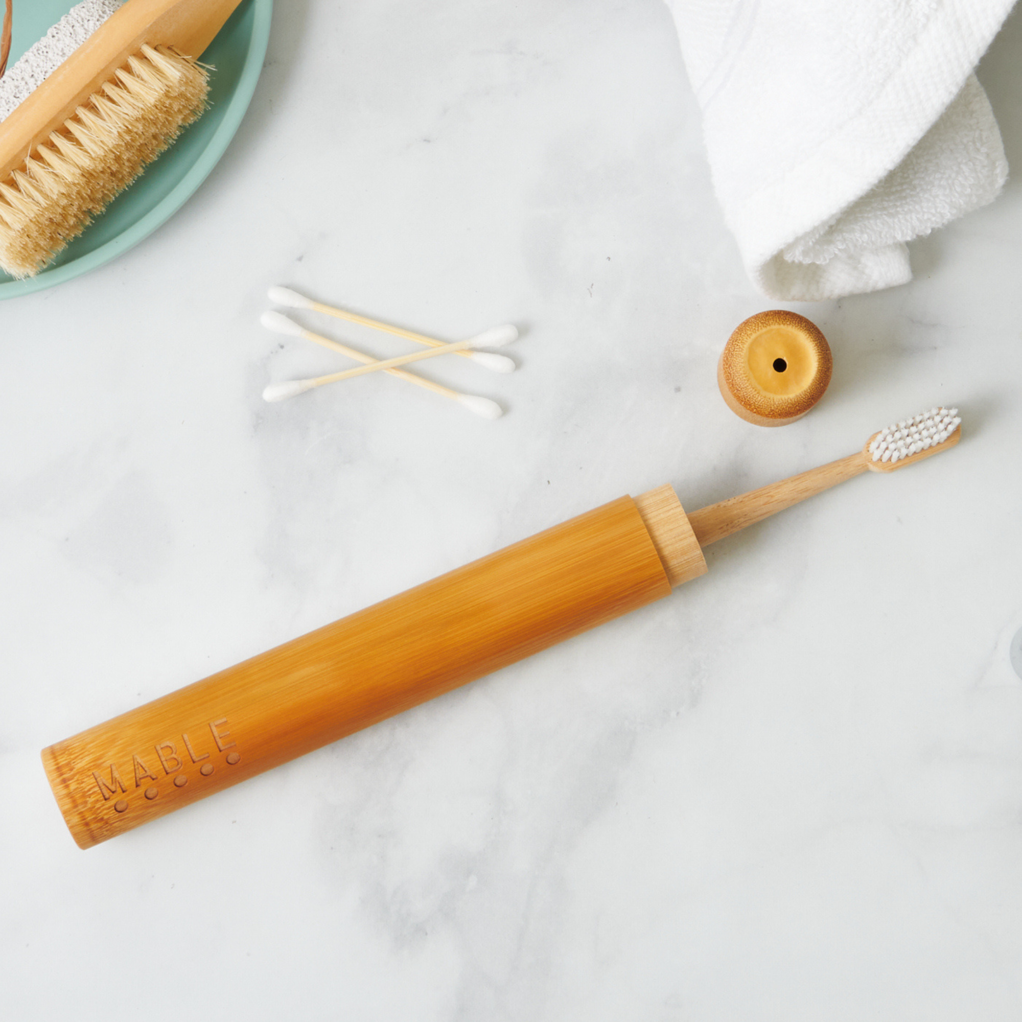 MABLE toothbrush travel container with Bamboo toothbrush with wooden handle on a marble surface