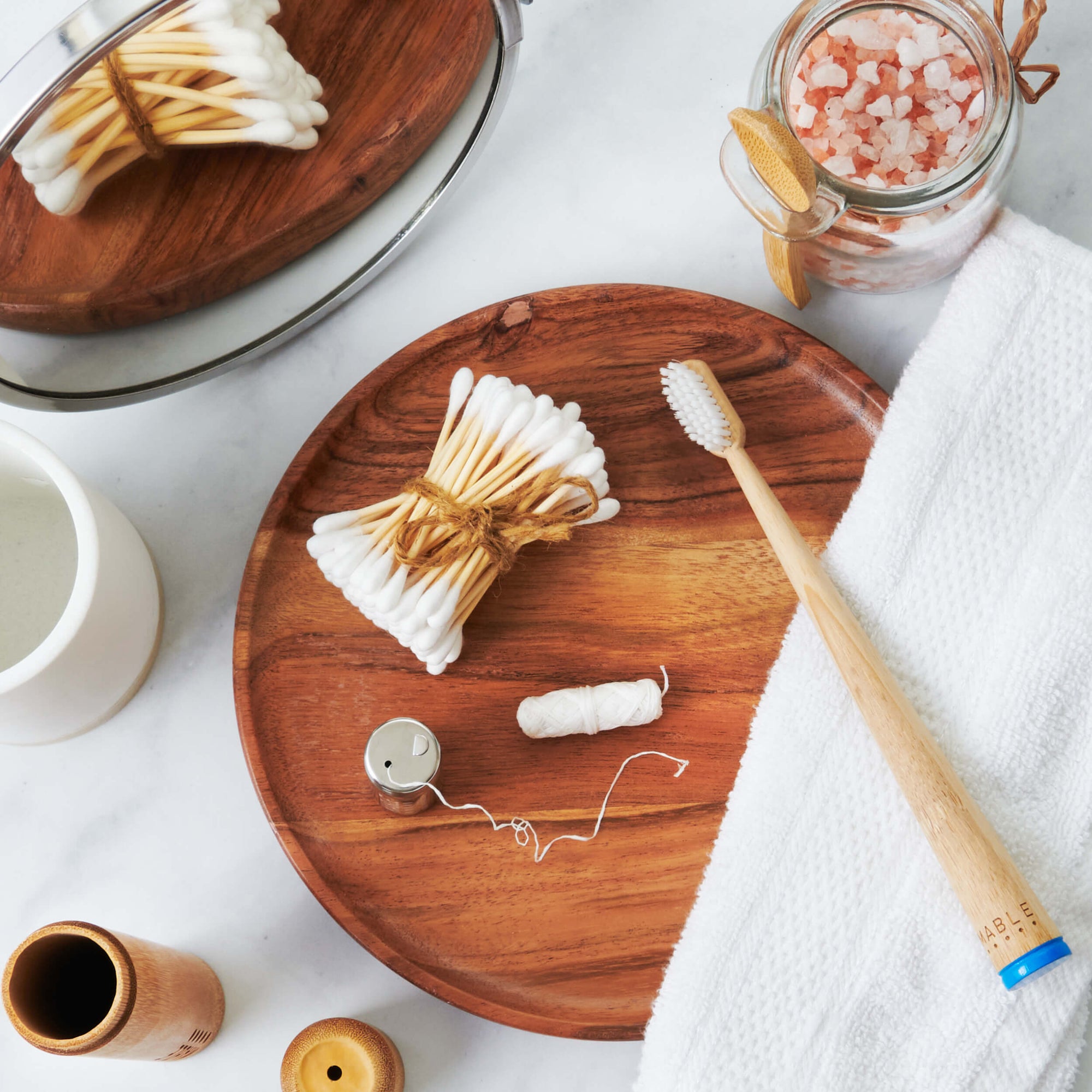 Sustainable bathroom routine with MABLE® Bamboo toothbrush blue brush, dental floss spool and stainless steel refillable floss container and bamboo cotton swabs.